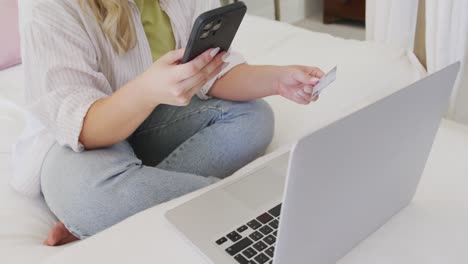 mujer caucásica de talla grande usando un teléfono inteligente y sosteniendo una tarjeta de crédito en cámara lenta