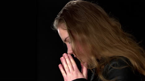 Young-woman-folds-her-hands-in-prayer-and-bends-her-head