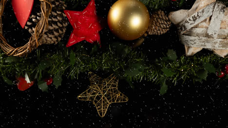 Animation-of-snow-falling-over-christmas-decorations-on-black-background