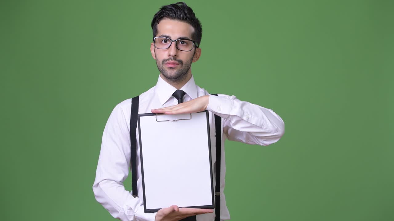 joven empresario persa barbudo y guapo contra un fondo verde