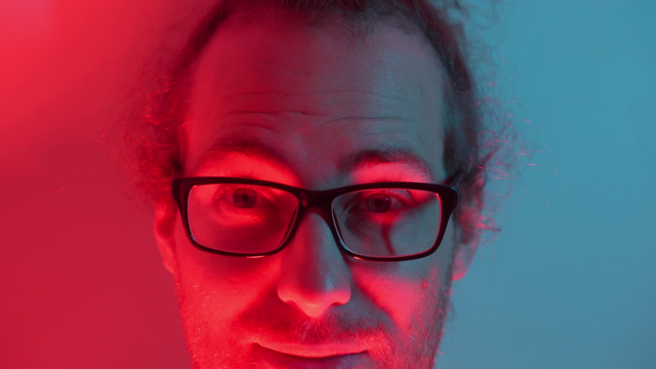 Close-up Portrait of a Man with Glasses in Red and Blue Light