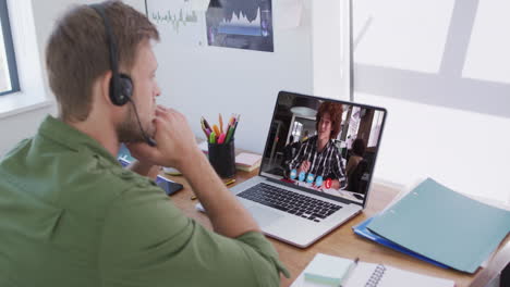 caucasian businessman sitting at desk using laptop having video call with male colleague