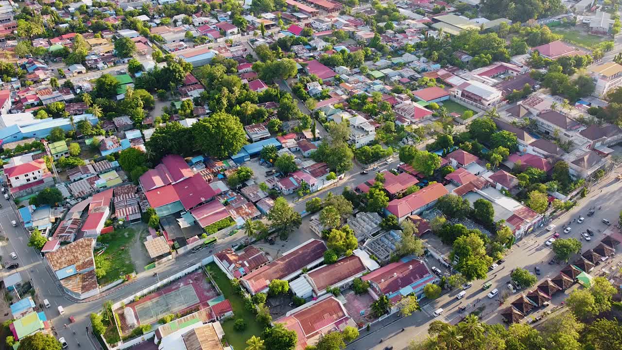Static aerial view above capital city of Dili, Timor-Leste with red tin rooftops, houses, and buildings with flowing traffic