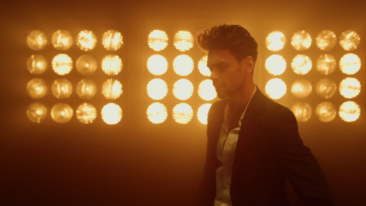 un hombre en primer plano moviéndose en un club nocturno. un tipo sexy posando bajo los reflectores.