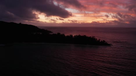 fiji islands - silhouette of the trees fringed on the sand surrounded by the wide ocean under the dramatic sky during sunset - glorious nature scenery - aerial drone shot