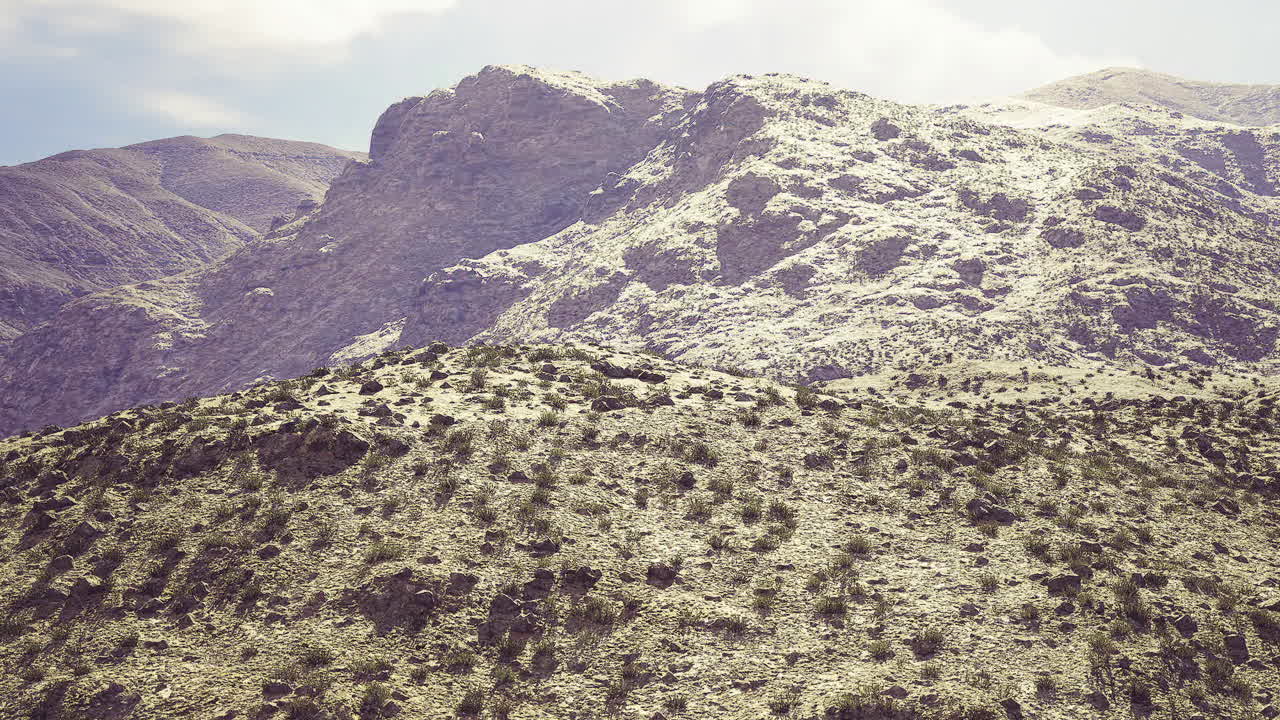 Colline serene sotto un cielo tenue, caratterizzate da minima attività umana e crinali aspri.