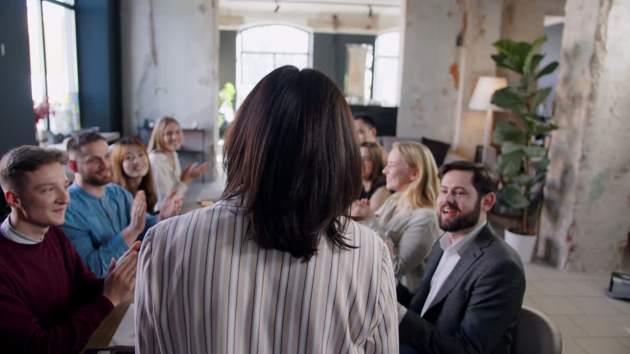 성공한 코치 사업가 여성은 트렌디한 로프트 사무실에서 세미나를 마친 후 다양한 직원 팀에 의해 박수를 받습니다.