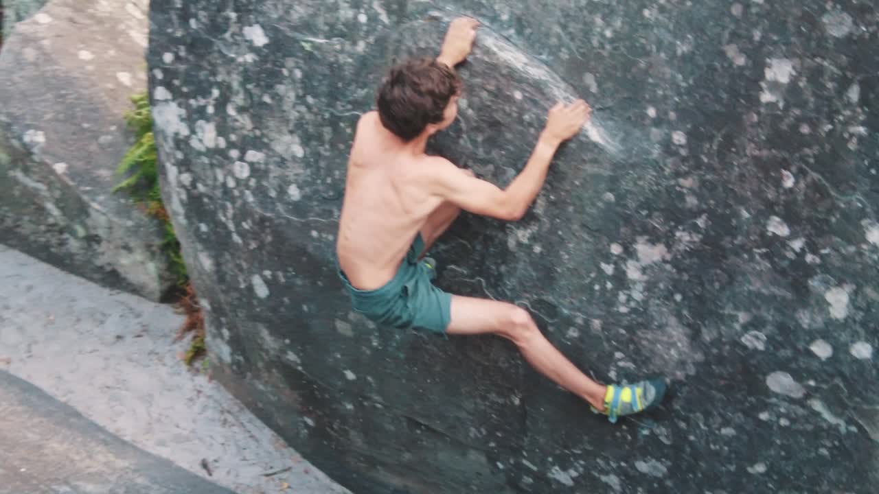 joven macho sin camisa escalada boulder fontainebleau se cuelga en movimiento técnico de borde