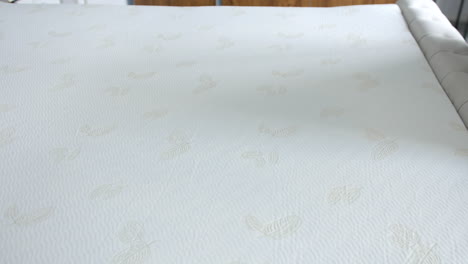 a mattress surface featuring a soft, white fabric with subtle embossed leaf patterns. close-up showing textured material and light stitching, highlighting fabric quality and detail