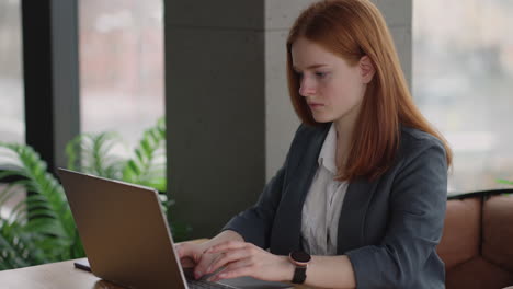 Una-Joven-Pelirroja-Está-Trabajando-En-Una-Computadora-Portátil.-Trabajo-Remoto.-Oficina-En-Casa.-Trabajo-De-Oficina.-Una-Mujer-Con-Traje-En-La-Oficina-Está-Escribiendo-En-Una-Computadora-Portátil