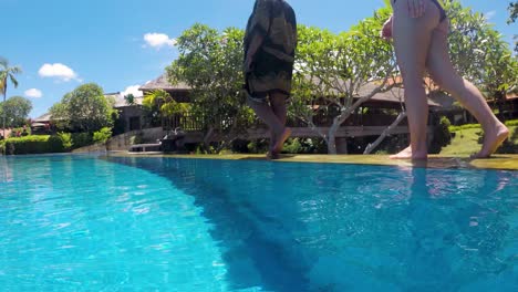 two young women walking casually along the swimming pool in luxury hotel in the popular travel destination bali. one woman is african american the other is caucasian