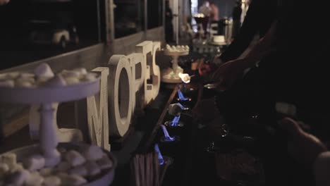 anonymous people roasting marshmallows at smores station at an event