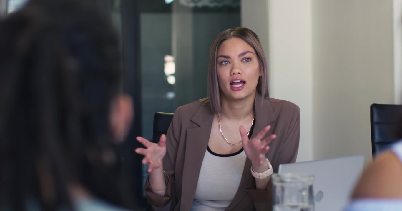 Coworkers listening while woman leading meeting, presenting on laptop, clarifying points