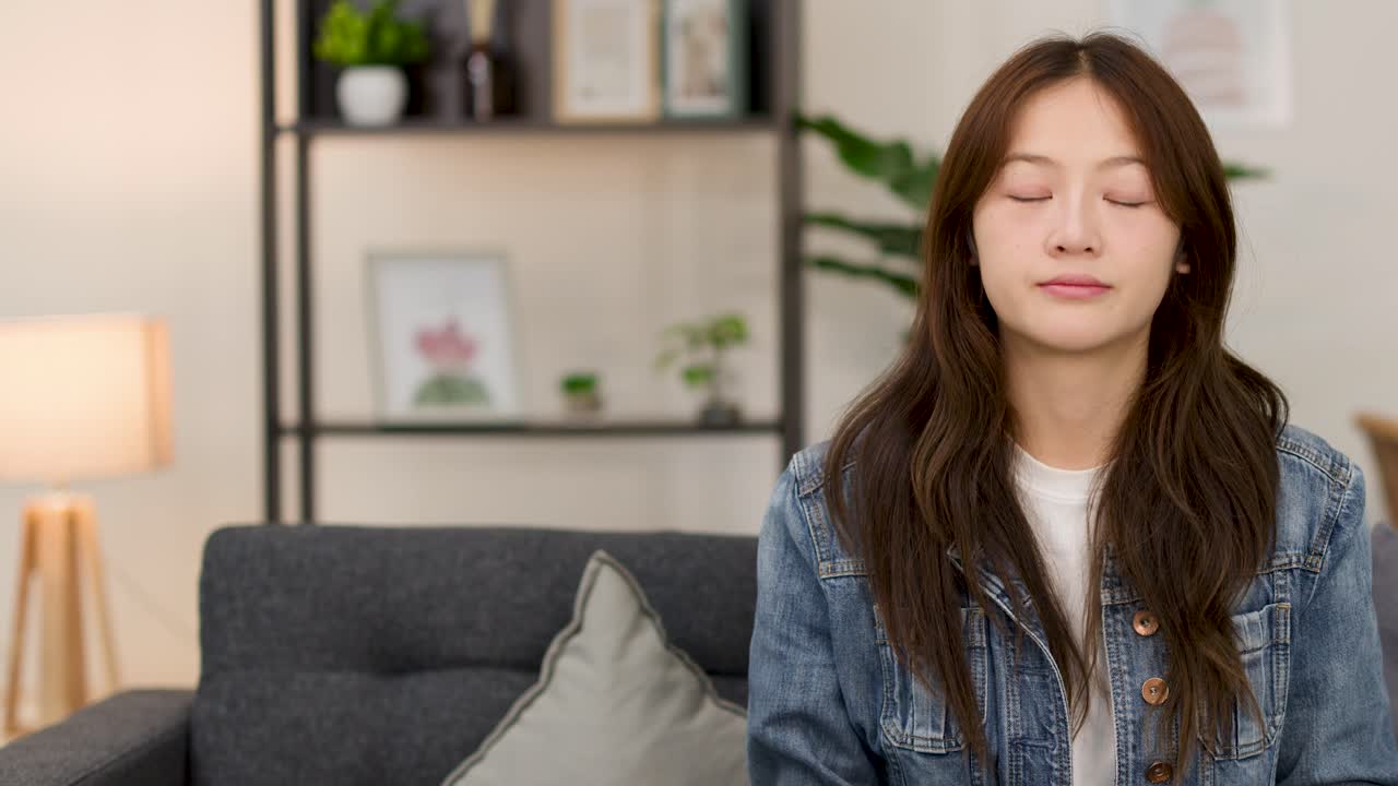 Young woman on couch shrugs with uncertain expression in bright indoor living room