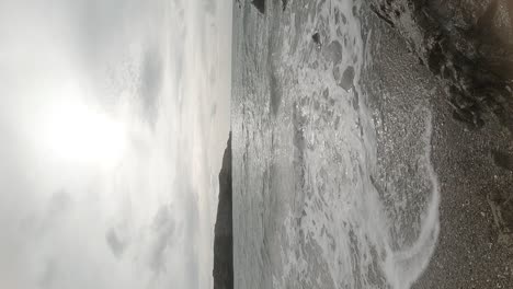 VERTICAL-slow-motion-ocean-waves-crashing-against-idyllic-rock-coastline-at-sunrise