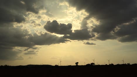 Silueta-De-Una-Planta-De-Energía-Eólica-Giratoria-Durante-La-Puesta-De-Sol-Con-Nubes