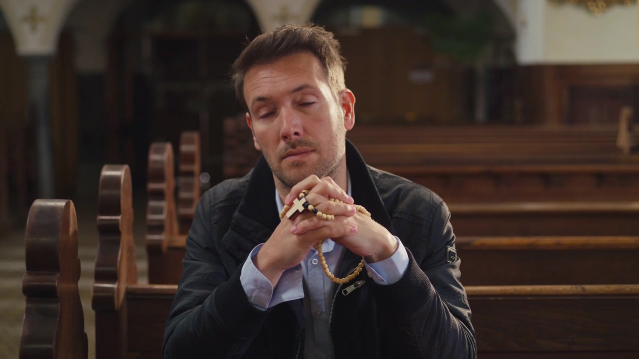 Momento particular de oração: um homem sentado em um banco de madeira em uma igreja cristã vazia e pacífica, orando