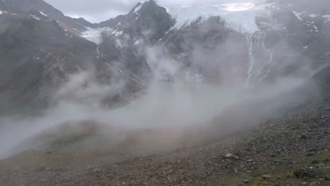 Clouds-and-fog-rolling-over-remote-high-alpine-lake-with-huge-glacier-above