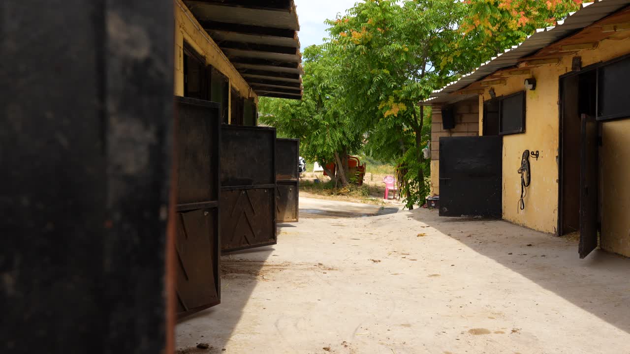 Panning right reveals multiple open stable doors in an equestrian center, 4K