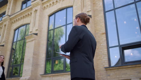 Man-using-tablet-in-motion-outdoors.-Businessman-walking-past-to-colleagues.