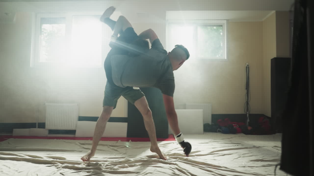 Athlete throws down partner at sparring in sports club. Young fighter attacks enemy exercising in foggy gym slow motion. Hand to hand combat training