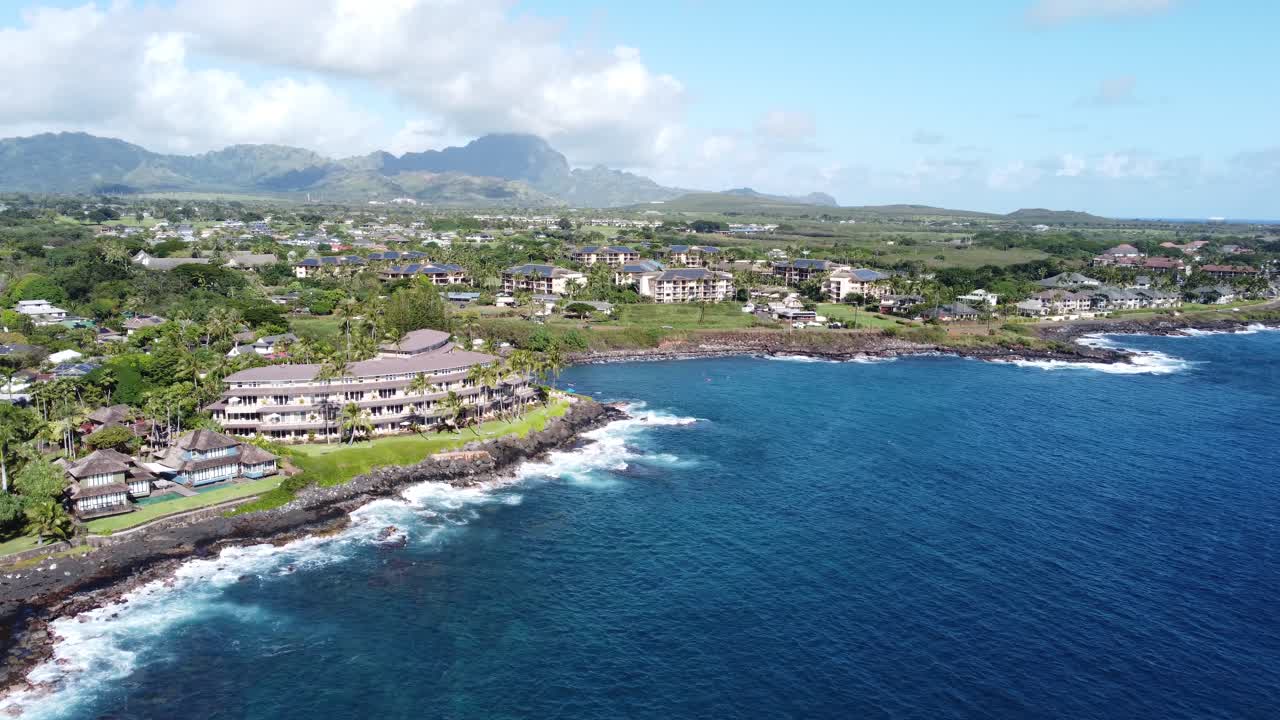 Aerial above capturing oceanfront resort hotels, beach, blue ocean and mountain landscape