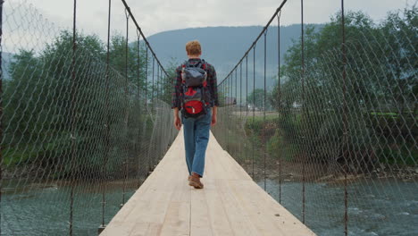 hiker walk river bridge at mountains landscape nature. backpacker enjoy tourism.