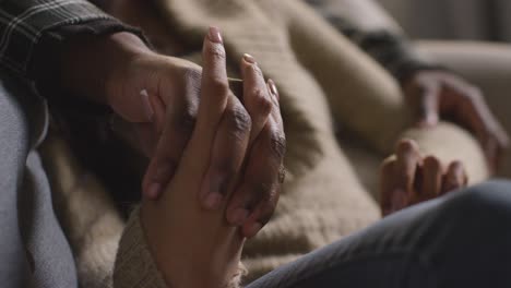 Close-Up-Of-Loving-Couple-Holding-Hands-Relaxing-At-Home-Sitting-On-Sofa-Talking-Together-1