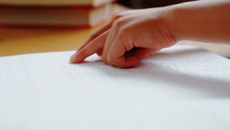 Close-up-of-blind-Asian-schoolboy-hand-reading-a-braille-book-in-classroom-at-school-4k