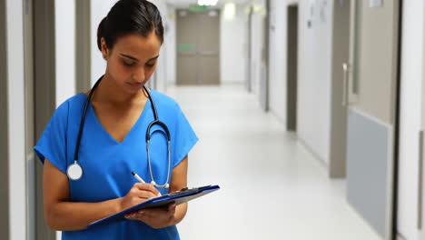 portrait of female doctor writing on clipboard