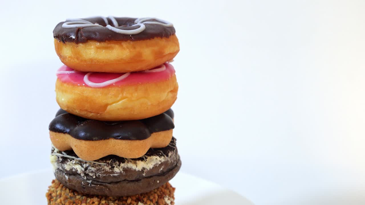 pila de sabrosas y dulces rosquillas de diferentes colores sobre un fondo blanco con copia de espacio de copia.