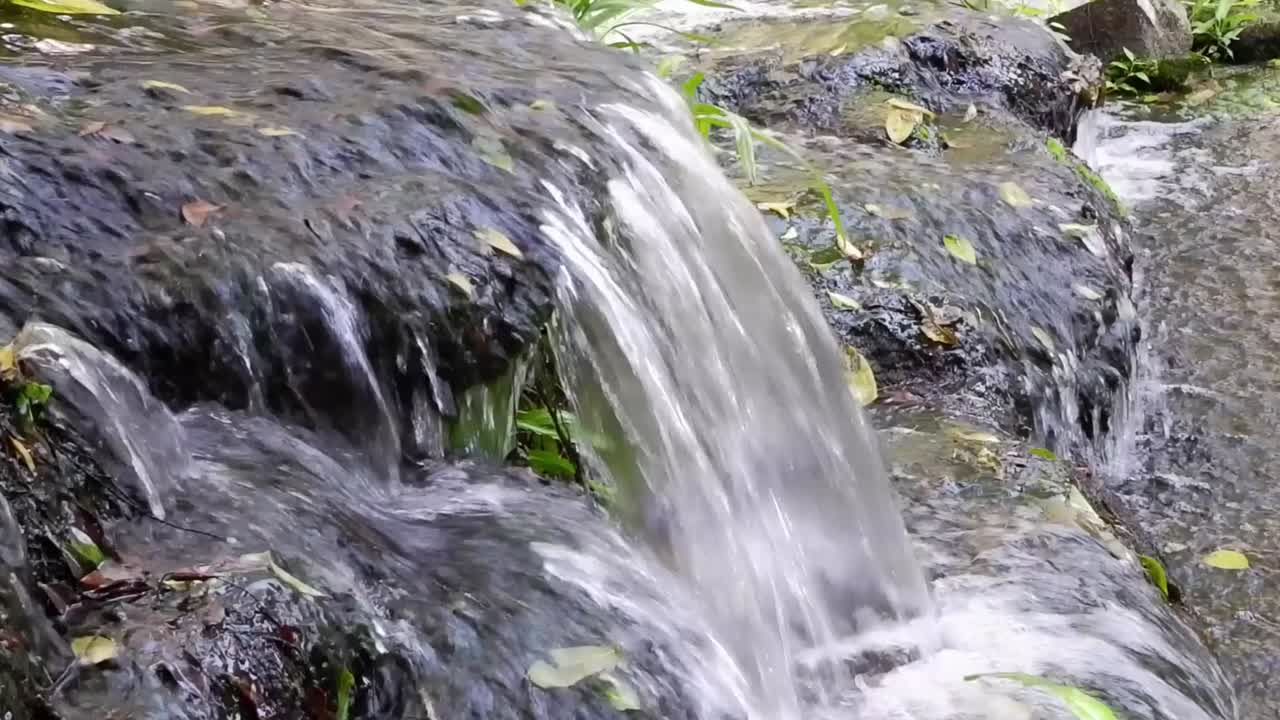A detailed view of water cascading over moss-covered rocks, highlighting the natural beauty and movement.