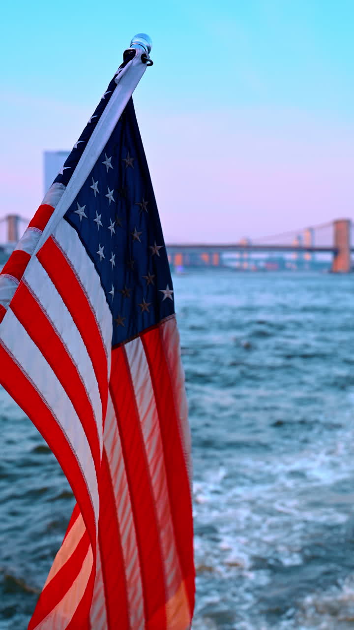 Albero maestro su una barca con bandiera americana. Paesaggio fluviale del fiume impetuoso sullo sfondo. Il ponte di Brooklyn sullo sfondo. Video verticale