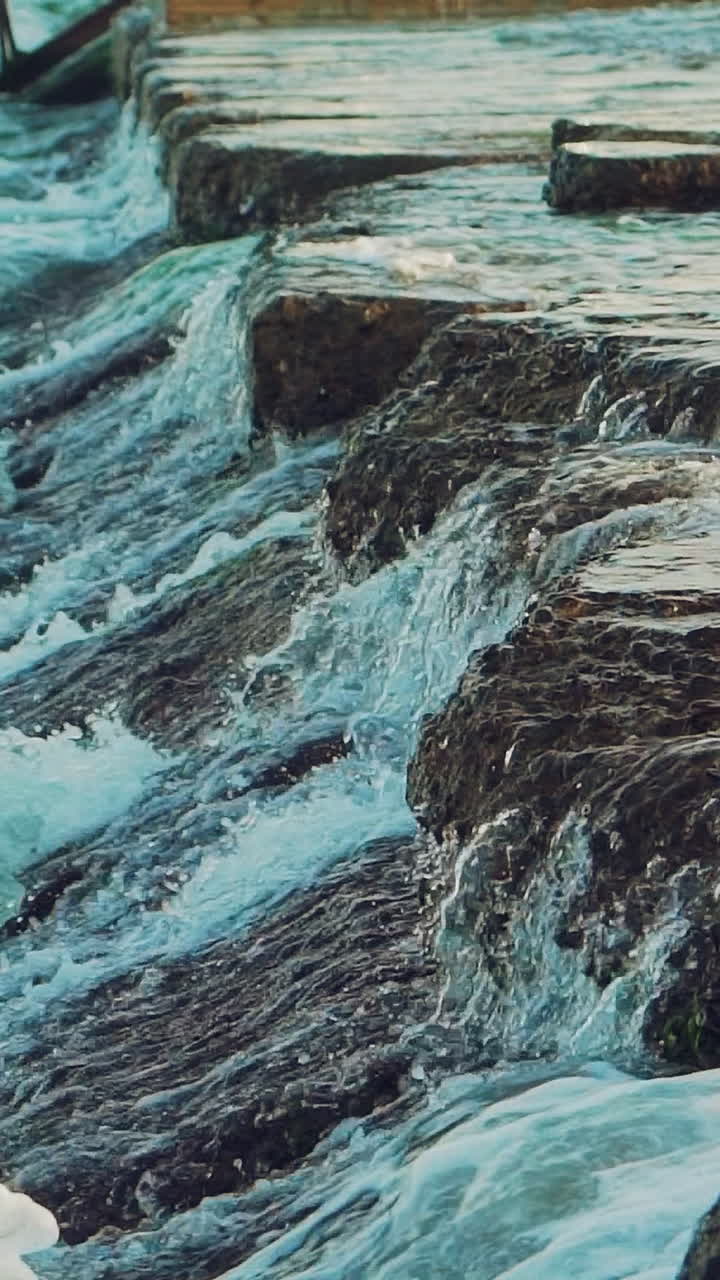 Waves are beating on the underwater reefs off the coast. Spray of water. Slow motion Vertical video
