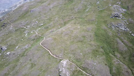 drone aerial view of a grassy mountain facade with a gravel path for walkers and mountaineers