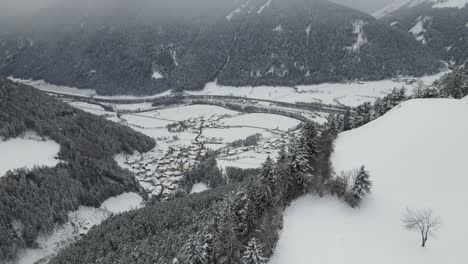 dunkler, launischer schneesturm in den italienischen alpen, man sieht ein kaltes tal und dorf