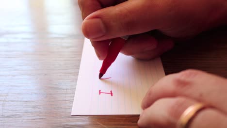 close up footage as male hands write a note using permanent marker pen on a small card of paper