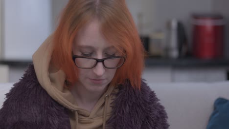 sad depressed woman sat on sofa with mug of tea