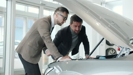 car salesman and customer inspecting a car