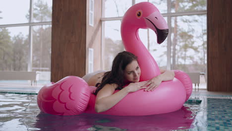 una mujer relajada está disfrutando de un día en un spa o centro de bienestar flotando en un flamenco inflable rosa en una piscina