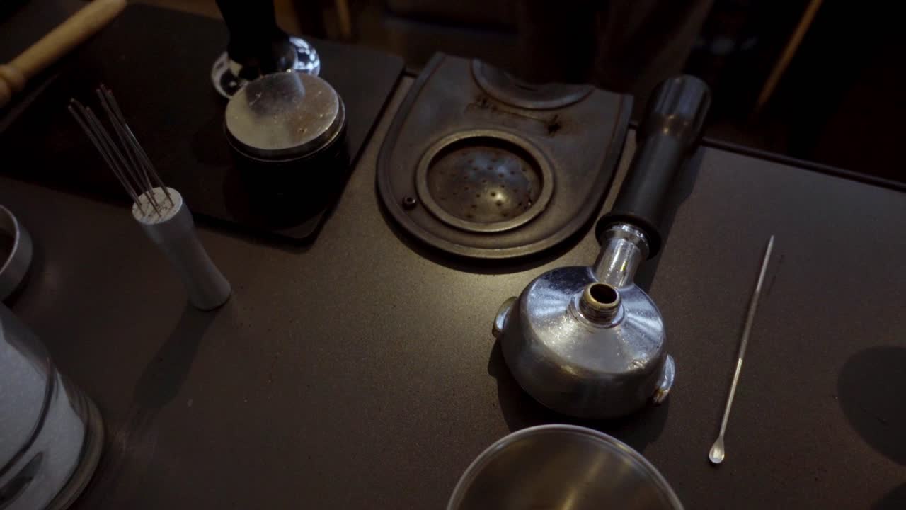 Detailed view of an espresso machine with portafilter and metal tools in a cozy coffee shop. Warm ambient lighting highlighting barista essentials for crafting perfect coffee