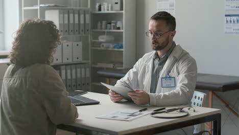 doctor greeting female patient, reading medical records and giving consultation