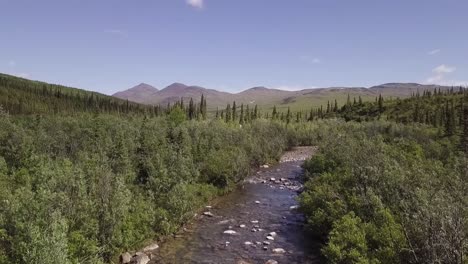 slow aerial lift off from beautiful small alaskan creek, looking across alaska tundra towards mt