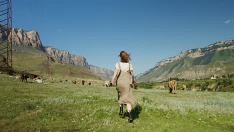 woman running in a mountain meadow with cows