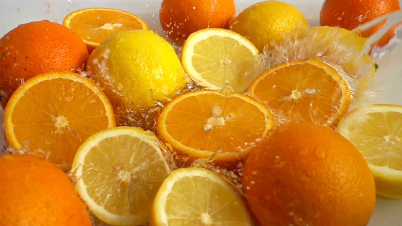 Laranjas e limões suculentos e salpicos. Câmera lenta
