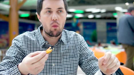 hombre comiendo comida en una sala de comidas de un centro comercial