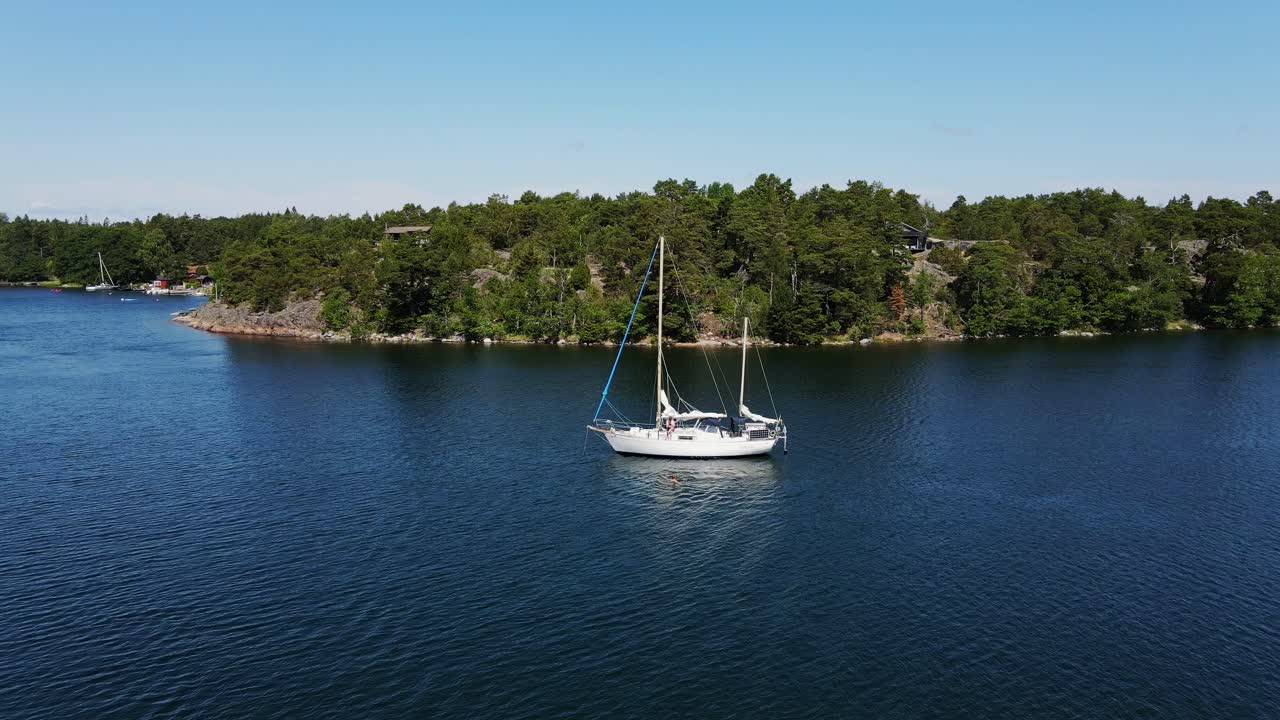 Drone shows peaceful yacht in Baltic inlet near trees in Stockholm, Sweden bay