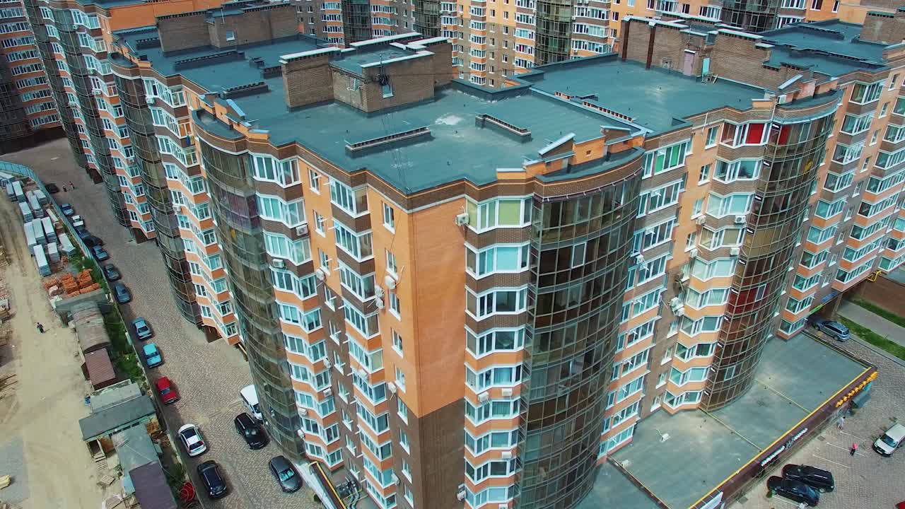 New apartment complex in the city. High-raised buildings near the road with moving cars. Modern infrastructure in downtown with car parking. Comfortable life in the city.