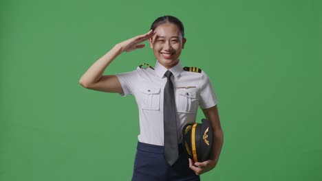 la piloto asiática es respetuosa, saludando mientras está de pie en el estudio de fondo de la pantalla verde