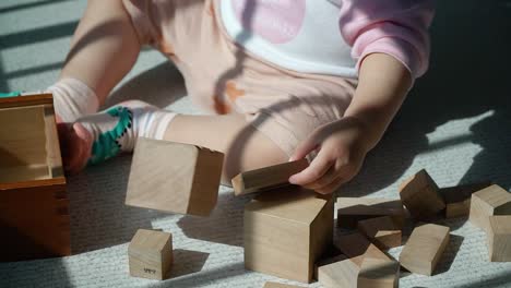 baby playing with toddler wooden blocks at the balcony staking up one on another - educational game for kids